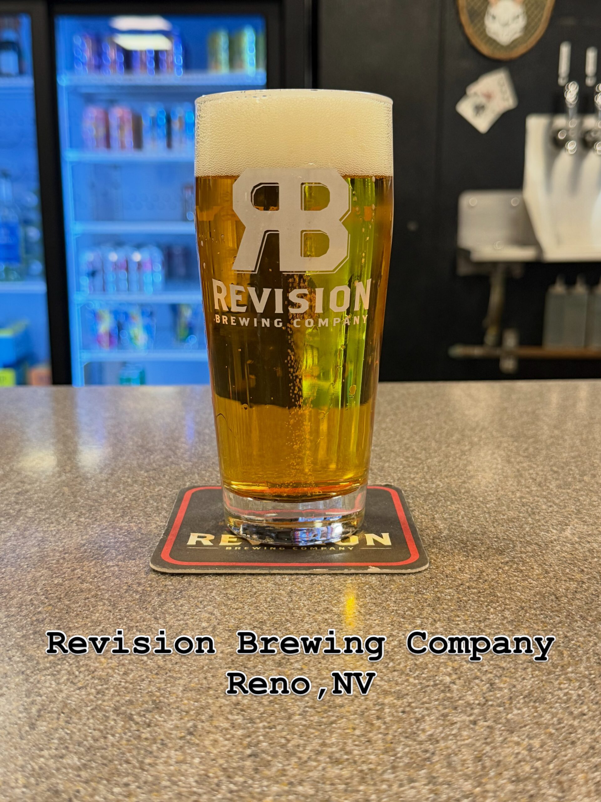 Revision Brewing Company のタップルームのカウンターに置かれた、ロゴ入りグラスのビール